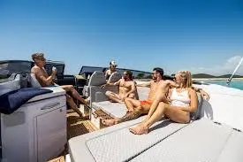 Groups of friends relaxing on a boat under a clear blue sky, enjoying the sun and the sea.